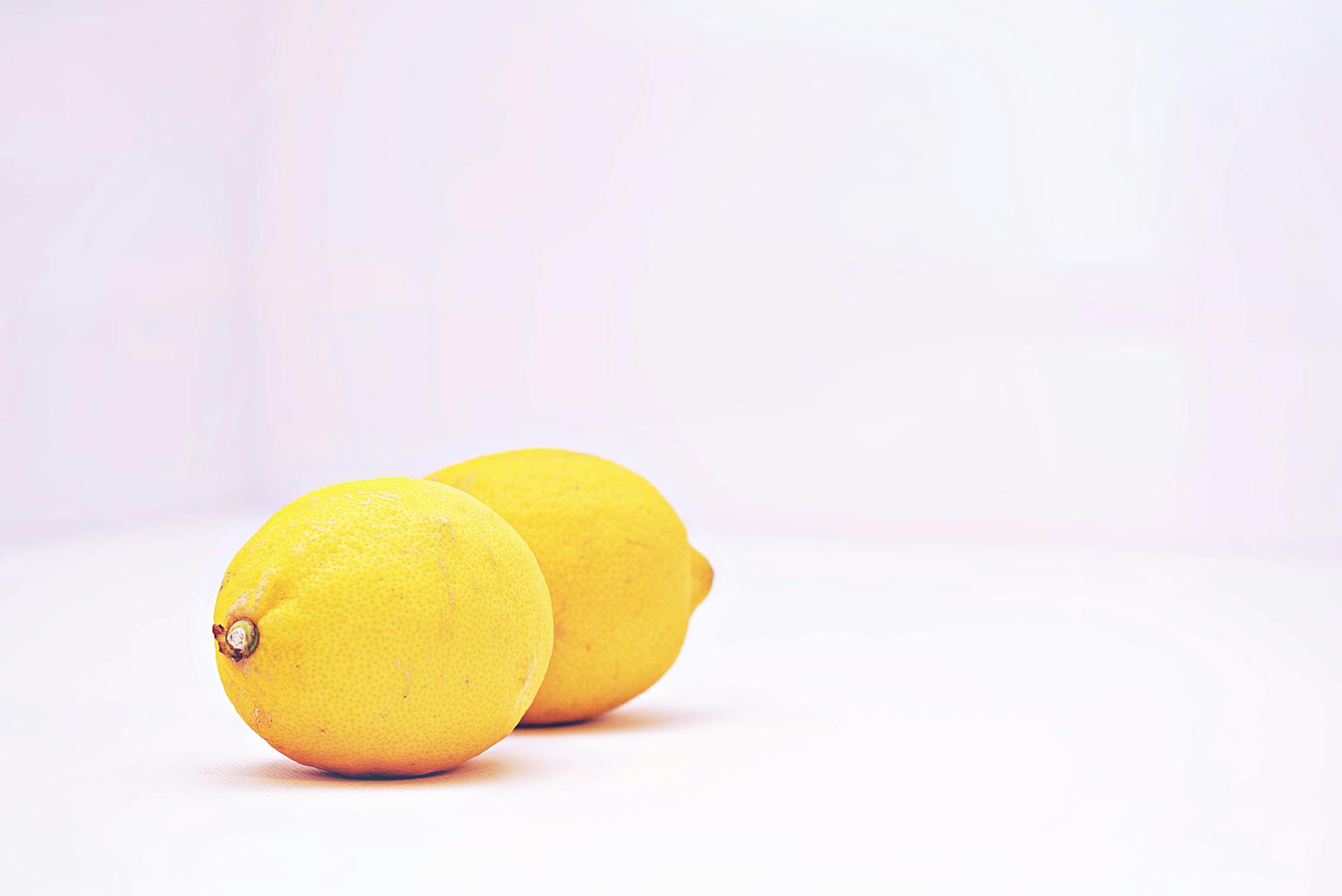 Dos limones vibrantes sobre fondo blanco minimalista, mostrando frescura y simplicidad