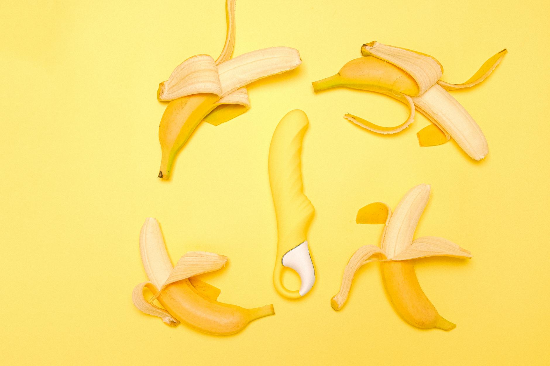 Vibrador de limón amarillo rodeado de limones frescos sobre fondo amarillo brillante