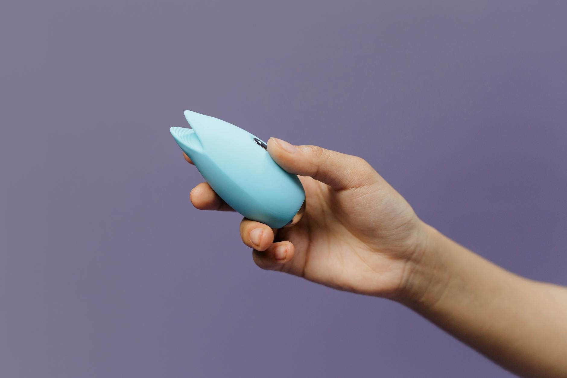 Pareja joven sosteniendo un vibrador azul juntos, simbolizando la intimidad moderna y la comunicación